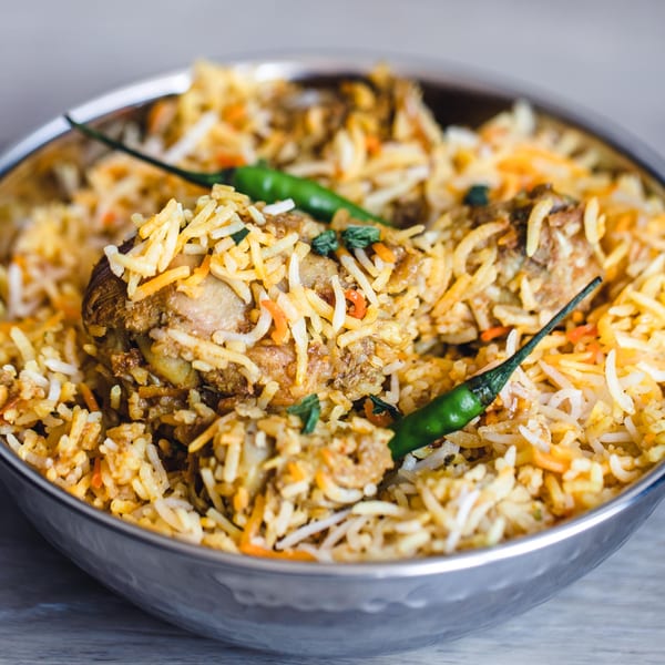 Chicken biryani with green chilies in a metal bowl from Tandoori Restaurant.